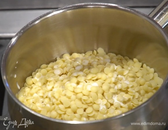 Белый шоколад всыпать в кастрюлю, влить сливки и, помешивая силиконовой или деревянной лопаткой, прогреть на медленном огне, не растапливая шоколад полностью, затем снять с огня и вымешать так, чтобы получилась шоколадная паста.