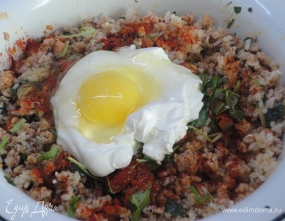 К фаршу добавить рис, яйцо, нарезанную зелень петрушки, 1 ч. л. паприки и 100 г сметаны. Перемешать.