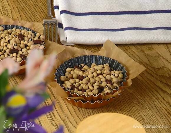 Вложить в формочки бумагу для выпечки, затем кружок теста и часто наколоть его вилкой, сверху поместить еще один слой бумаги и еще одну формочку, всыпать в нее любые бобовые.