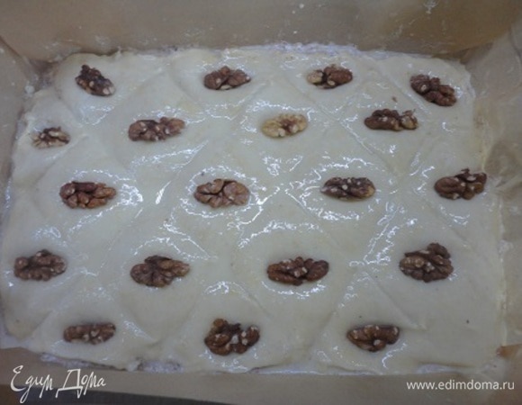 Смазать желтком с молоком и сделать разметку обратной стороной ножа. Украсить дольками орехов.
