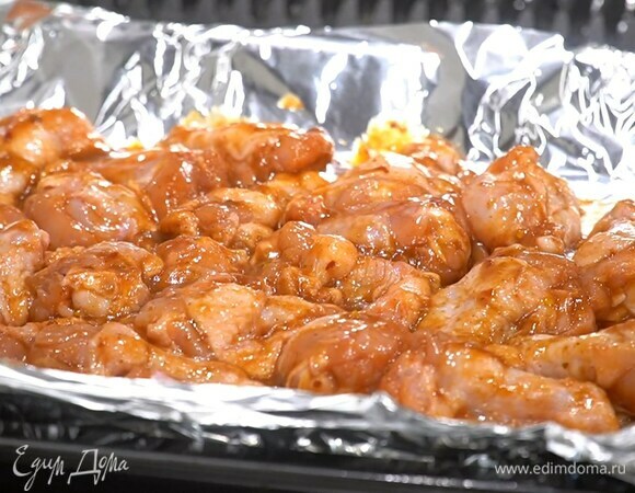 Противень выстелить фольгой и равномерно разложить крылышки.