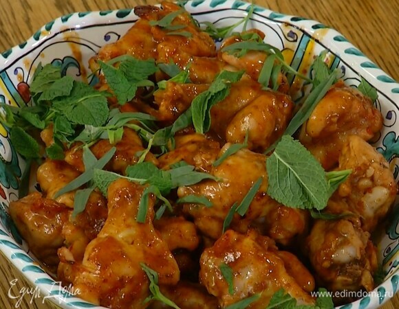 Готовые крылья переложить на тарелку, полить оставшимся в противне соусом и украсить листьями тархуна и мяты.