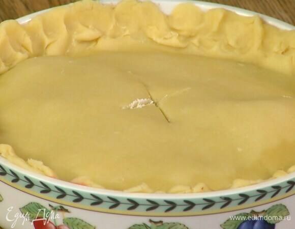 Оставшееся тесто на бумаге для выпечки раскатать в тонкий пласт, рыть им корж с начинкой и скрепить края так, чтобы получился небольшой бортик, в центре сделать крестообразный надрез.