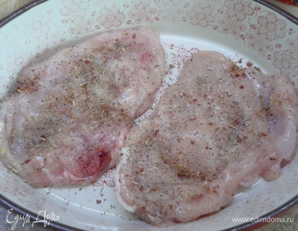 Включить духовку на 200°C. Грудки слегка отбить, посолить, поперчить, посыпать смесью пряных трав. Помидор с помощью кипятка очистить от кожицы и нарезать кольцами. Лук тоже нарезать кольцами и обжарить на сильно разогретом растительном масле.