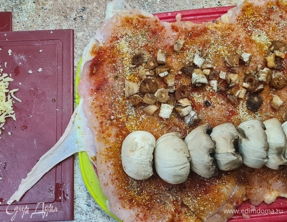 Распределяем подготовленную шкурку на столе, нарезаем примерно одинакового размера и толщины мясо и выкладываем на шкурку. Мясо посыпать специями, выложить грибы, тертый сыр, чернослив, скрутить в рулет.