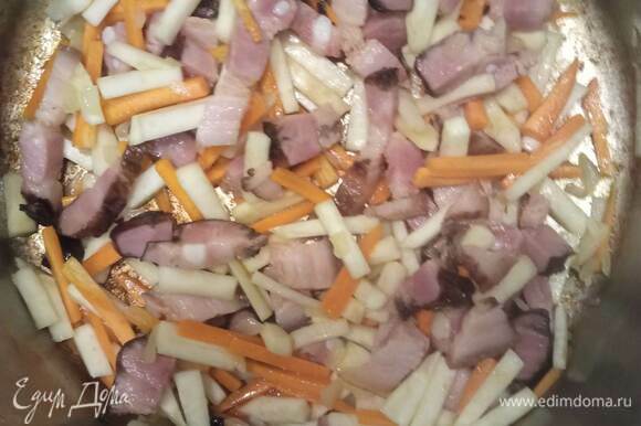 Лук мелко шинкую. Картофель, морковь и корень сельдерея нарезаю брусочками. Также режу грудинку. И обжариваю грудинку в кастрюле с толстым дном на растительном масле, постоянно помешивая, 5 минут. Добавляю морковь, лук и сельдерей и готовлю, продолжая помешивать, 4 минуты.