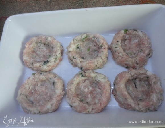 Разделите фарш на равные части (по 80 г). Вначале сформируйте шарики, выложите их на противень или в форму для запекания. Затем с помощью стакана, окуная его в воду, сделайте углубления. Слоеное тесто нарежьте полосками.