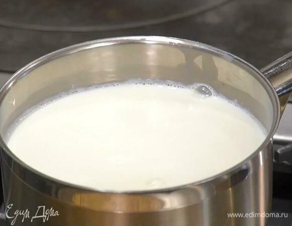 Молоко влить в кастрюлю и прогреть на небольшом огне до 40℃, затем всыпать закваску и все перемешать.