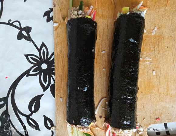 Свернутый рулет разглаживаем руками от центра к краям. Смазываем кисточкой кунжутным маслом. Даем полежать пару минут и нарезаем очень острым ножом на кусочки 1–1,5 см шириной. Края кимпаба оставляем как есть с торчащими овощами. При подаче посыпаем кунжутом.