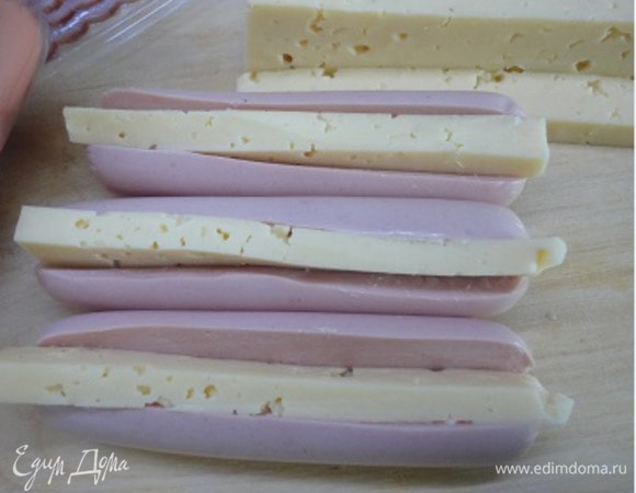 Сосиски разрезать вдоль и в разрезы вложить кусочки сыра.