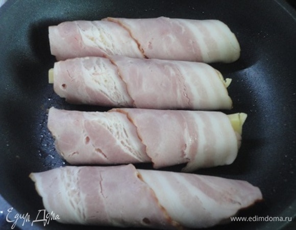 Фаршированые сосиски обернуть кусочками бекона или грудинки и обжарить на сковороде.