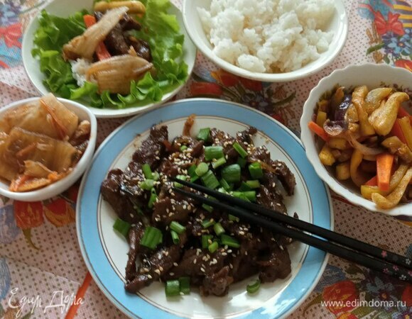 Подают пулькоги с рисом и закусками панчан. Сверху посыпают семенами кунжута и мелко нарезанным зеленым луком. У меня это кимчи и кабачки. Можно посмотреть рецепты закусок здесь: https://www.edimdoma.ru/retsepty/150807-kimchi и https://www.edimdoma.ru/retsepty/150365-kabachki-po-koreyski. В ресторанах пулькоги обычно подают на чугунных сковородках. Если у вас есть такие (можно взять обычную чугунную сковородку), тогда сначала обжарьте на ней еще репчатого лука, чуть-чуть посыпанного сахаром, а сверху выложите мясо.