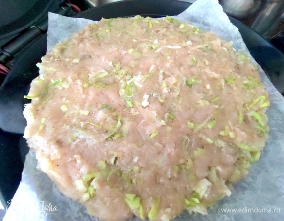 На камень для пиццы положить пергамент и распределить фарш ровным слоем.