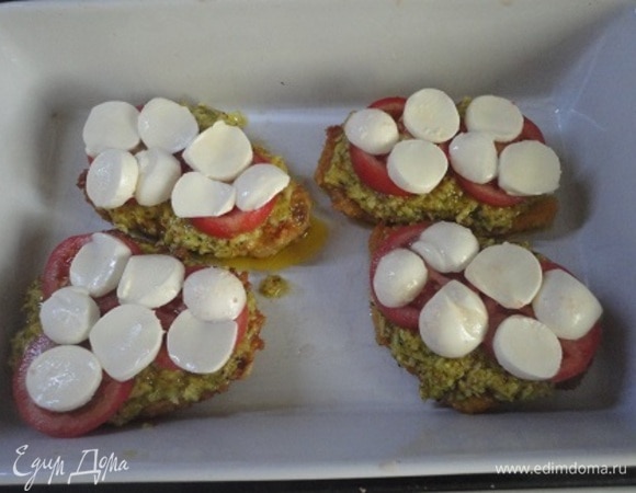 Отбивные поместить в посуду для запекания, на них выложить соус, дольки помидора или половинки черри, сверху выложить ломтики моцареллы.