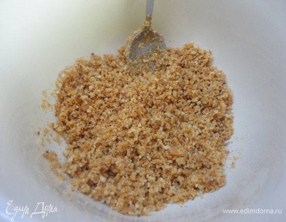 Разогрейте духовку до 180°C. Сливочное масло растопите и остудите до комнатной температуры. Насыпьте в маленькую миску сухари, вылейте на них сливочное масло и перемешайте вилкой.