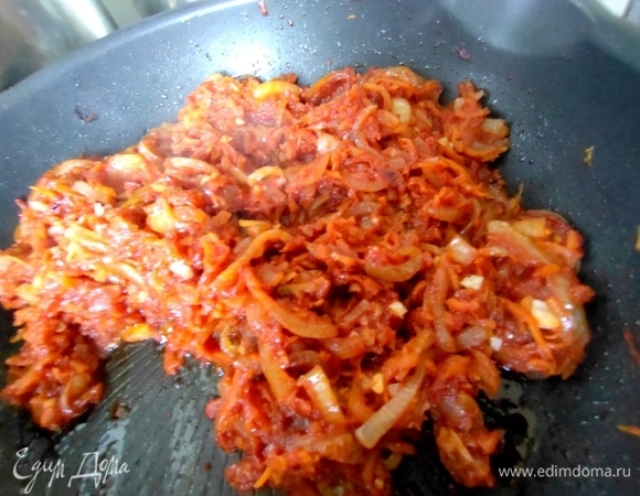 Добавить размороженную морковь к луку вместе с чесноком.