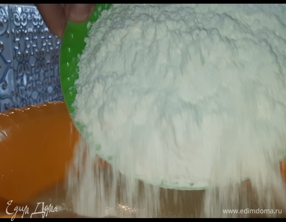 Частями добавьте муку, сначала замешивайте ложкой в емкости, а затем на столе. В конце муки добавляйте все меньше и меньше. Замешивайте тесто 10 минут. Оно должно получиться очень мягкое.