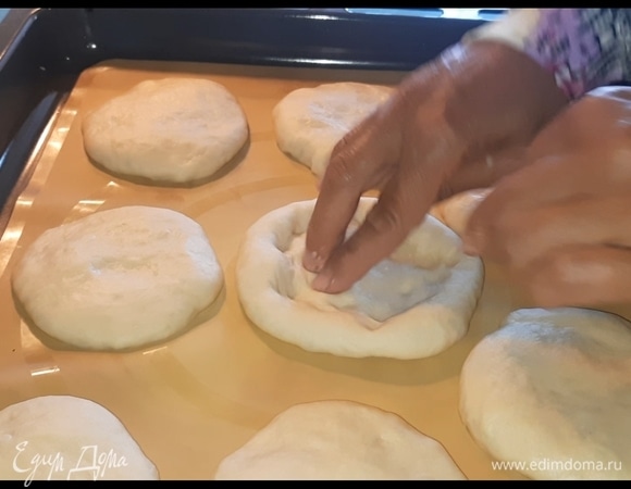 После того как тесто поднимется, руками сделайте углубления в лепешках.