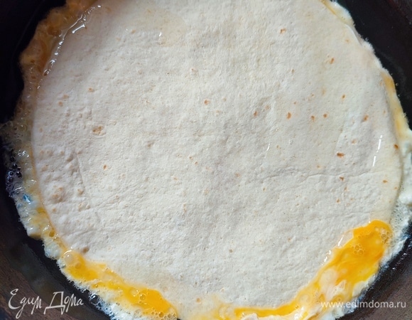 Сковороду с подсолнечным маслом разогреть. Взбить два яйца вилкой до однородности и вылить в сковороду, сразу же сверху положить одну тортилью.