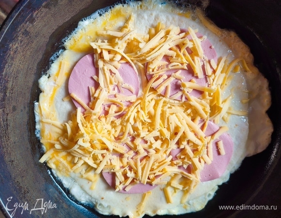 На тортилью выложить четыре кружочка колбасы и посыпать сыром. Сверху выложить еще одну тортилью.