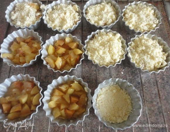 В каждую формочку для кексов всыпать по столовой ложке масляно-мучной крошки. У меня получилось 14 формочек. Слегка утрамбовать. Добавить по небольшой порции яблочной начинки. Посыпать яблочную начинку в каждой формочке столовой ложкой масляно-мучной крошки.