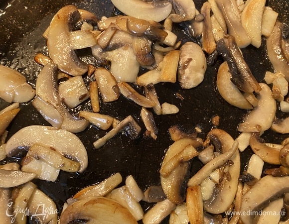Отдельно обжариваем грибы на оставшемся масле с целыми зубчиками чеснока. Желательно обжаривать в несколько этапов, покрывая грибами только дно сковороды, чтобы грибы не давали воду.