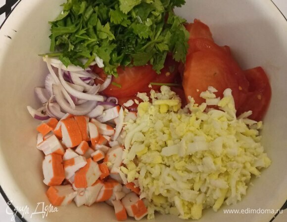 Отвариваем яйца, чистим их и трем на крупной терке или мелко шинкуем. Помидор режем тонкими дольками, лук — полукольцами, крабовые палочки — не очень мелко, кинзу шинкуем мелко. Вместо кинзы можно взять петрушку, если не любите.