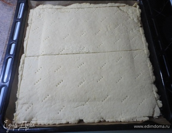 Испеченный корж еще горячим сразу разрезать пополам, а неровные края подровнять. Обрезки выложите в противень и уберите в выключенную духовку.