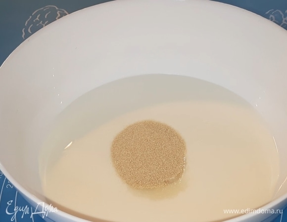 Всыпьте в кефир сахар, дрожжи, перемешайте, накройте крышкой и дайте постоять 15 минут при комнатной температуре (за это время на поверхности должна образоваться пенка).