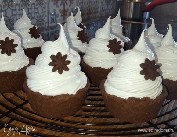 Щедро распределите крем на поверхности корзиночек с помощью кондитерского мешка с насадкой и украсьте цветочками из остатков теста.