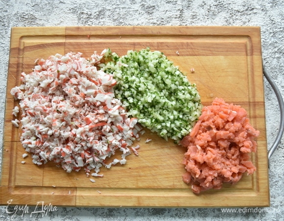 Пока варится рис, подготовьте вкусовые добавки. Как можно мельче нарежьте свежий огурец, рыбу и крабовые палочки.