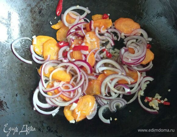 Лук режем очень тонкими полу- или четверть-кольцами, морковь — очень тонкими пластинами немного наискосок, перец чили и оставшийся чеснок мелко шинкуем. Если боитесь остроты, удалите у перца семена и перегородки. В воке разогреваем растительное масло до очень высокой температуры, закидываем морковь, жарим на большом огне, постоянно помешивая, 1 минуту, добавляем лук, чеснок и перец чили, жарим 30 секунд.