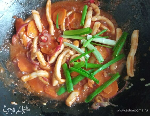 Добавляем приготовленную заправку и нарезанный зеленый лук. Лук режем не очень мелко, перышками по 2,5–3 см. Обжариваем все вместе еще 2 минуты. Важно не передержать кальмаров, иначе они станут резиновыми. В конце можно добавить 1 чайную ложку кунжутного масла.