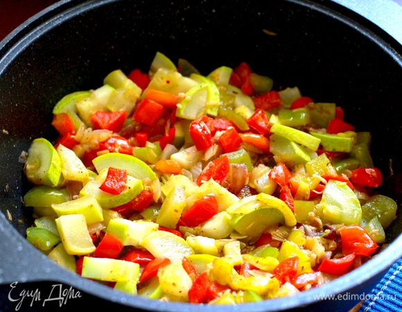 В широком сотейнике на оливковом масле обжарить до прозрачности нарезанный лук, добавить чеснок и пожарить вместе 2 минуты. Добавить поочередно нарезанные овощи: перец, жарить 2 минуты, кабачок, перемешать и жарить, помешивая, 10 минут под крышкой. Приправить солью, перцем и остальными специями. Добавить кетчуп лечо ТМ «Махеевъ» и перемешать.