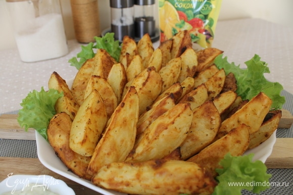 Готовые дольки картофеля выкладываем на блюдо на листья салата, украшаем по желанию зеленью. Соус подаем в соуснице отдельно. Приятного аппетита!