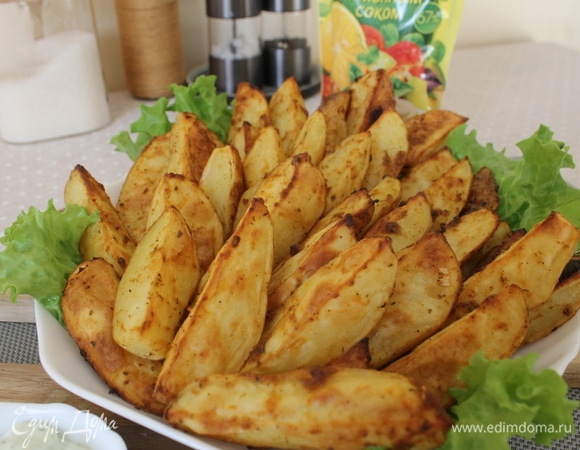Готовые дольки картофеля выкладываем на блюдо на листья салата, украшаем по желанию зеленью. Соус подаем в соуснице отдельно. Приятного аппетита!