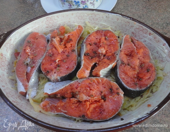 Форму для запекания смажьте сливочным маслом и выложите половину овощей. Сверху разложите кусочки рыбы.