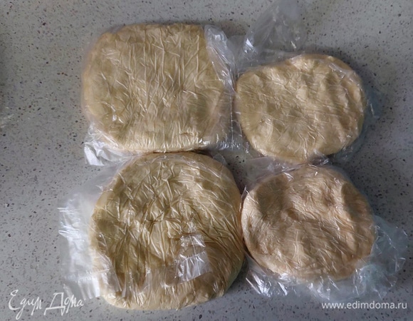 Разделяем тесто на 4 части. Две из них делаем побольше, это будет основа пирога, еще две — поменьше, это верхушка. Упаковываем в пакеты и отправляем в морозилку.