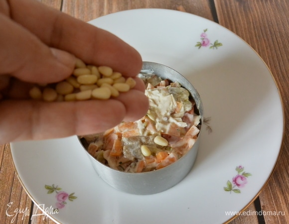 Посыпать салат кедровыми орешками.
