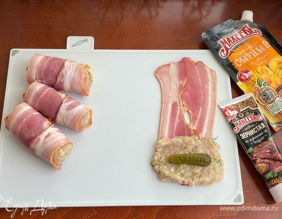 Фарш разделите на 9 одинаковых частей. Две полоски бекона уложите на доску. Влажными руками из фарша сформируйте лепешку. Вложите внутрь корнишон и сформируйте котлету. Котлету положите на один край полосок из бекона и заверните рулетиком.