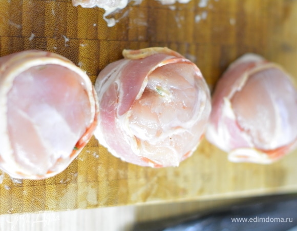 На середину каждого филе положить немного зелени и шарик сыра. Собрать края кверху. Обернуть беконом по кругу немного в нахлест. Перевернуть «шайбочки» швом вниз.