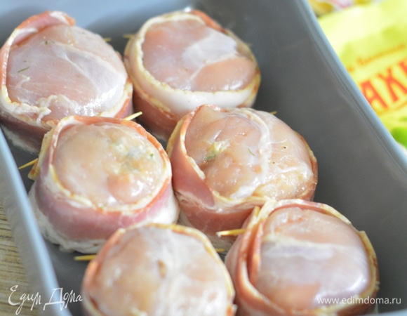 Скрепить зубочисткой бекон. Уложить «шайбочки» в форму, смазанную маслом, и запечь в духовке 20–30 минут до румяного цвета и характерного аромата. Немного остудить и удалить зубочистки.