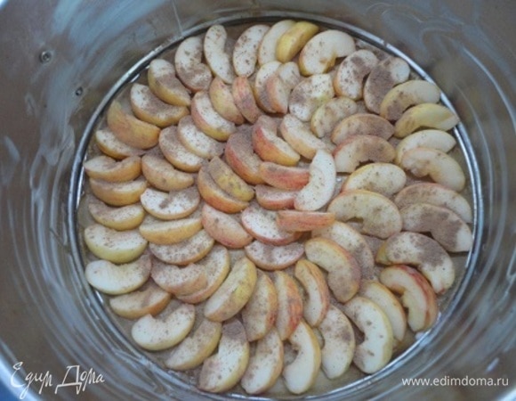 Начинаем с начинки. Разъемную форму диаметром 18–20 см смазать маслом. На дно можно уложить пекарскую бумагу. Выложить яблоки и посыпать их корицей. Включить духовку для разогрева на 180°C.