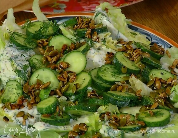 Айсберг нарезать крупными кусками и выложить в тарелку, полить заправкой и маринадом от огурцов, сверху разложить огурцы и семечки.