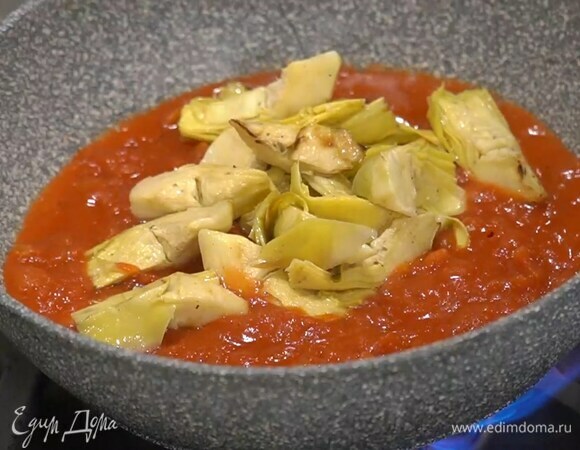 В сковороду, где жарилась индейка, выложить помидоры, артишоки, влить оставшееся оливковое масло и все прогреть.