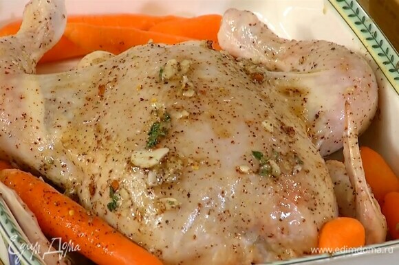 Тушку курицы поместить в жаропрочную керамическую форму грудкой вверх и кисточкой смазать медовой смесью снаружи и внутри, по бокам разложить морковь.