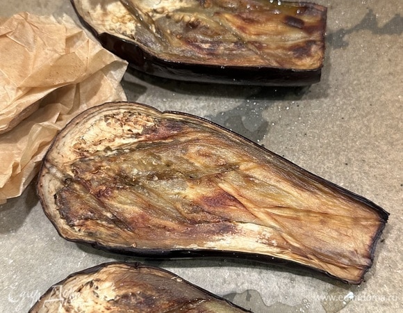 Моем, подсушиваем и разрезаем баклажаны пополам. Делаем неглубокие надрезы крест накрест, немного солим, сбрызгиваем оливковым маслом и отправляем в духовку, разогретую до 220°C, на 40–45 минут. Даем им немного остыть.