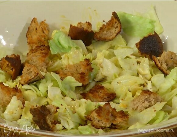 Листья айсберга выложить в глубокий салатник, смазать заправкой, сверху разложить крутоны.