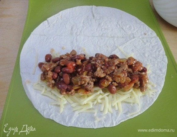 Делим мясную смесь и половину натертого сыра на 6 частей, выкладываем на каждую лепешку и плотно заворачиваем рулетом. Выкладываем в подготовленную форму.