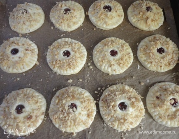 Во второй половине сделайте отверстия. Этими кружочками накройте те, что с начинкой, и с помощью вилки скрепите края. Выложите печенье на противень, застеленный пекарской бумагой. Смажьте сверху яйцом и посыпьте измельченными грецкими орехами. У меня получилось 18 шт. и немного обрезков.